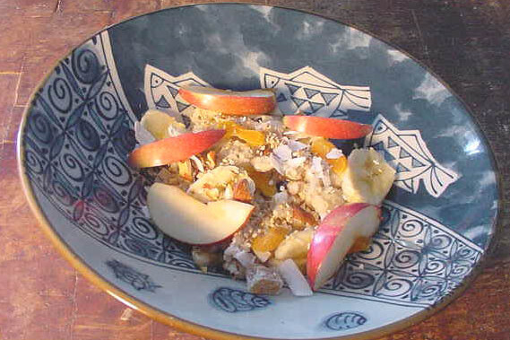 Bowl full of brown rice oat hot cereal with sliced apples on top