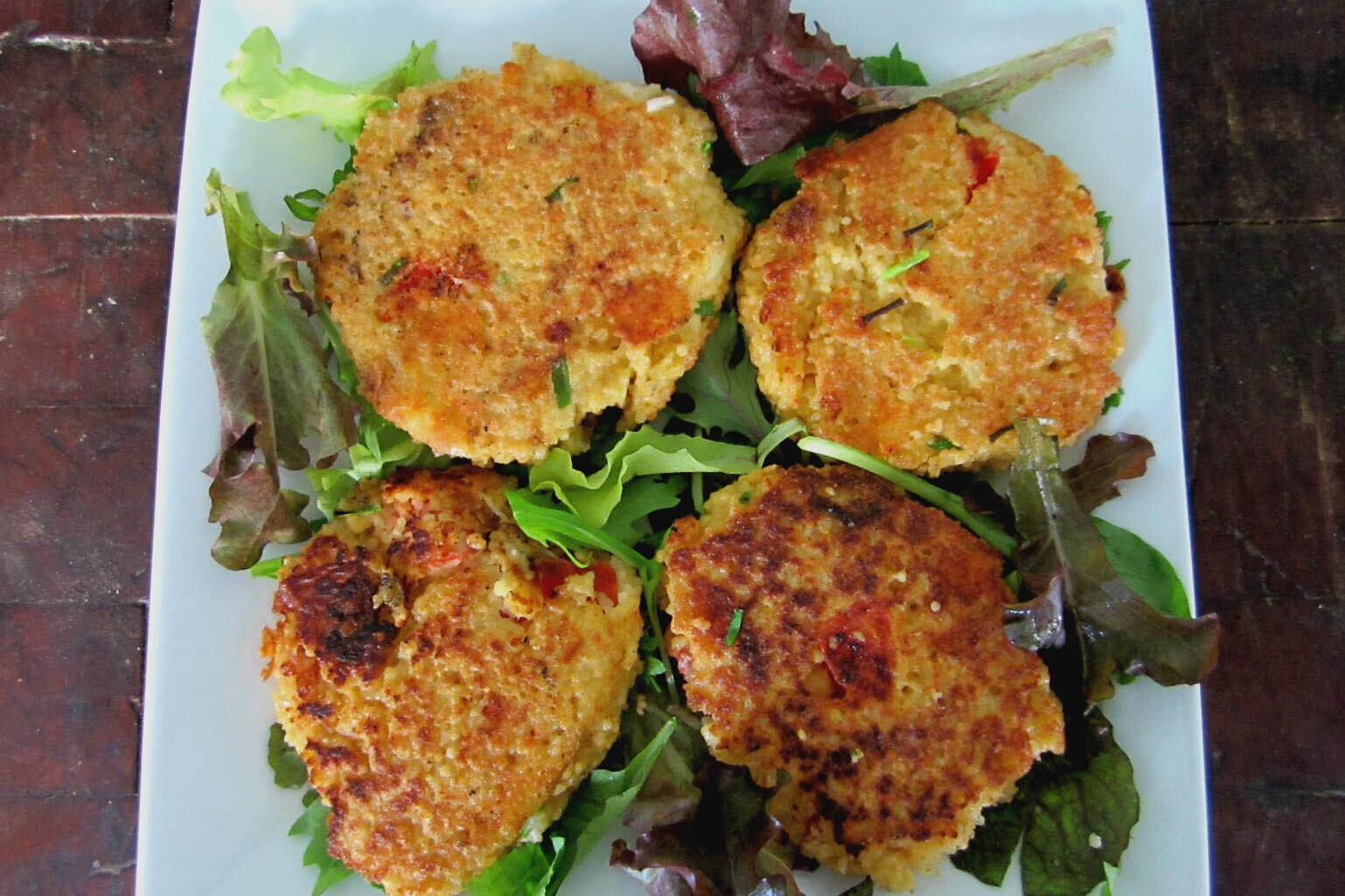 Four tomato whole wheat couscous cakes on a bed of lettuce