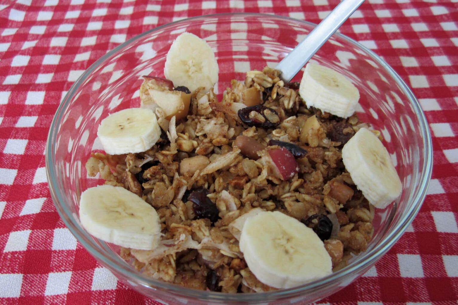 A bowl full of granola topped with sliced bananas