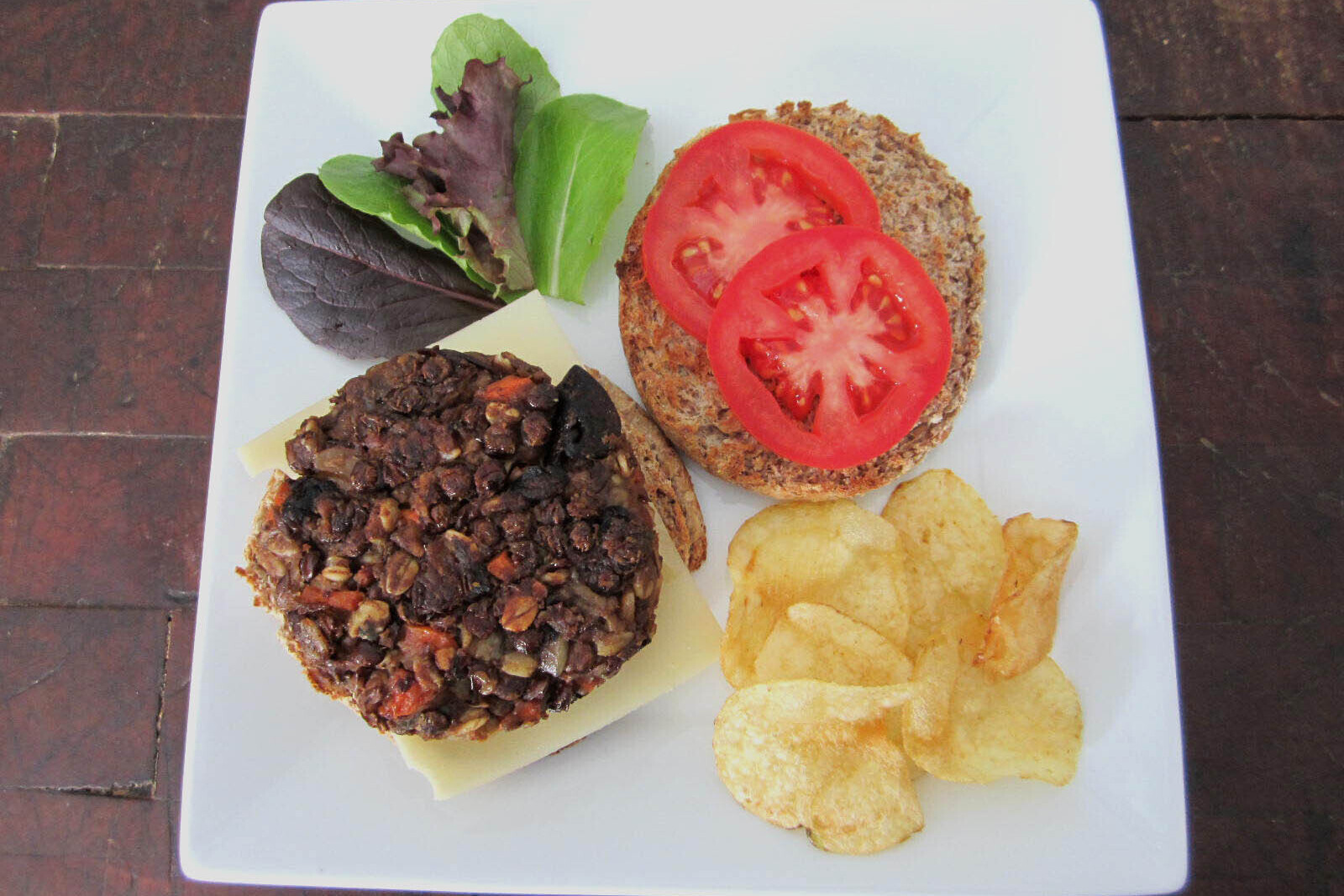 Lentil carrot burgers with cheese, tomatoes, lettuce and chips on the side