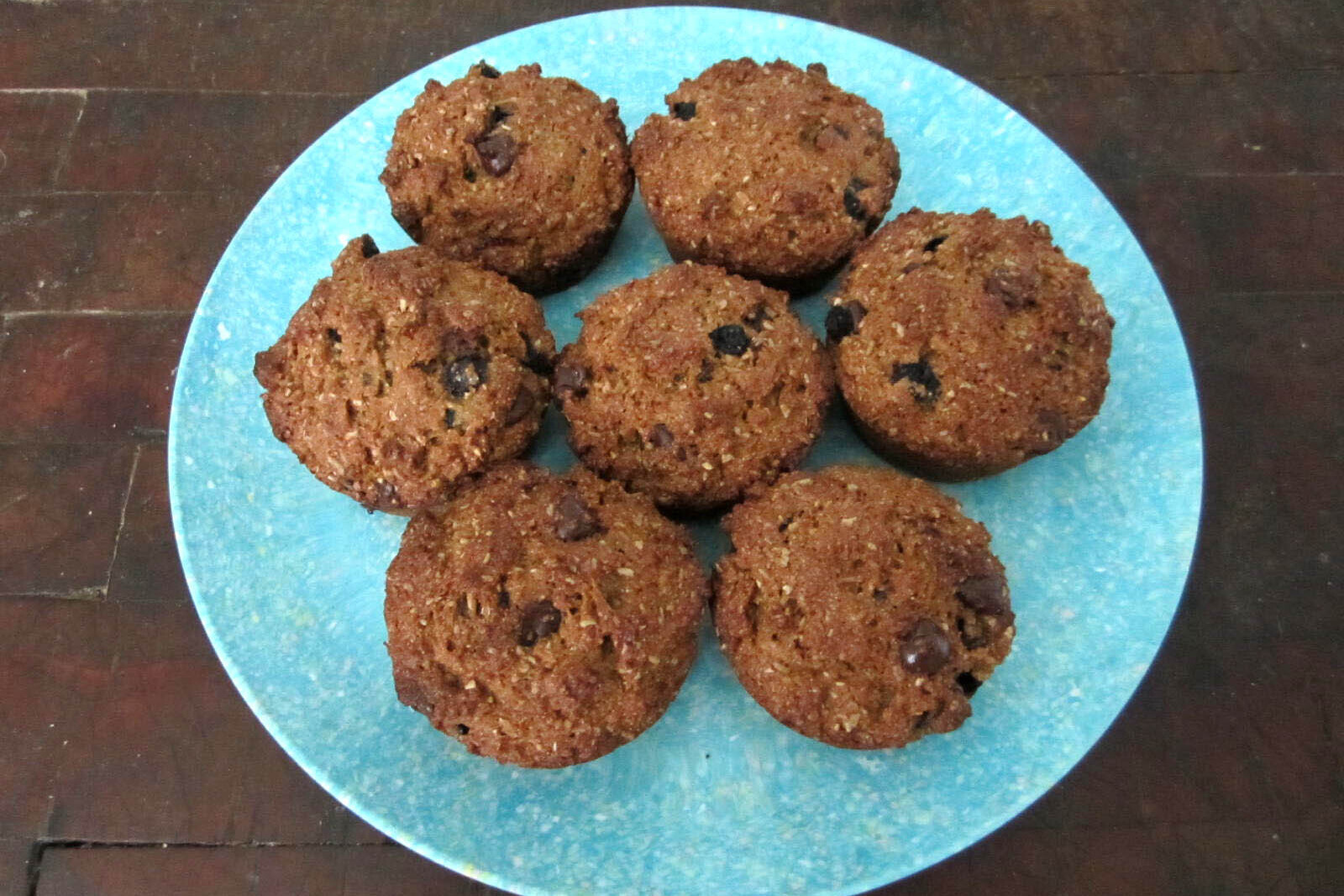 Seven bran muffins with blueberries and chocolate on a blue plate