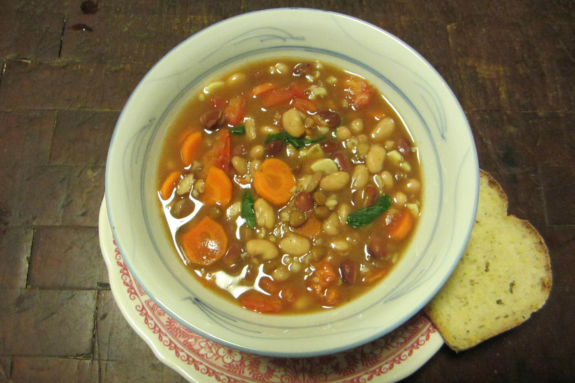 Bowl of vegetable bean soup with a slice of bread on the side