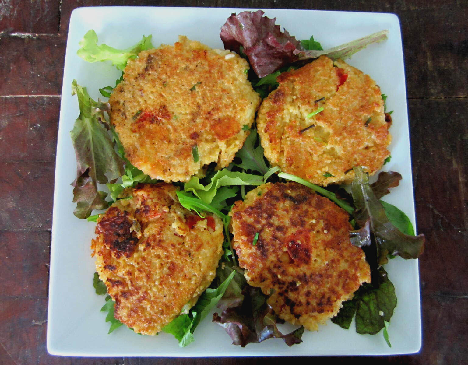 Four tomato whole wheat couscous cakes on a bed of lettuce