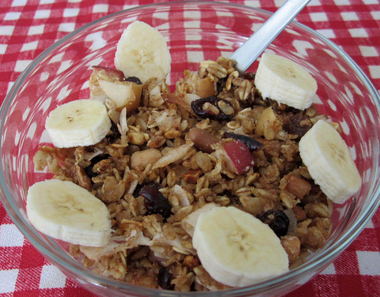 A bowl full of granola topped with sliced bananas