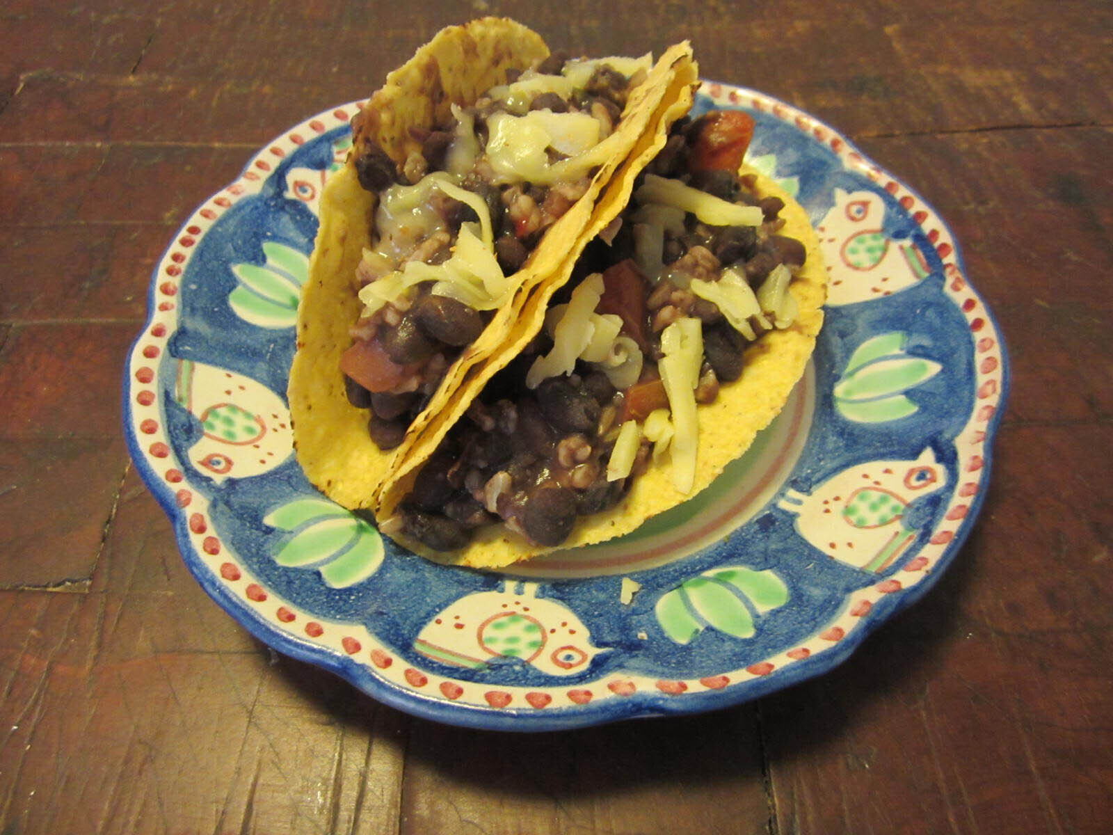 Two black bean tacos with cheese on top