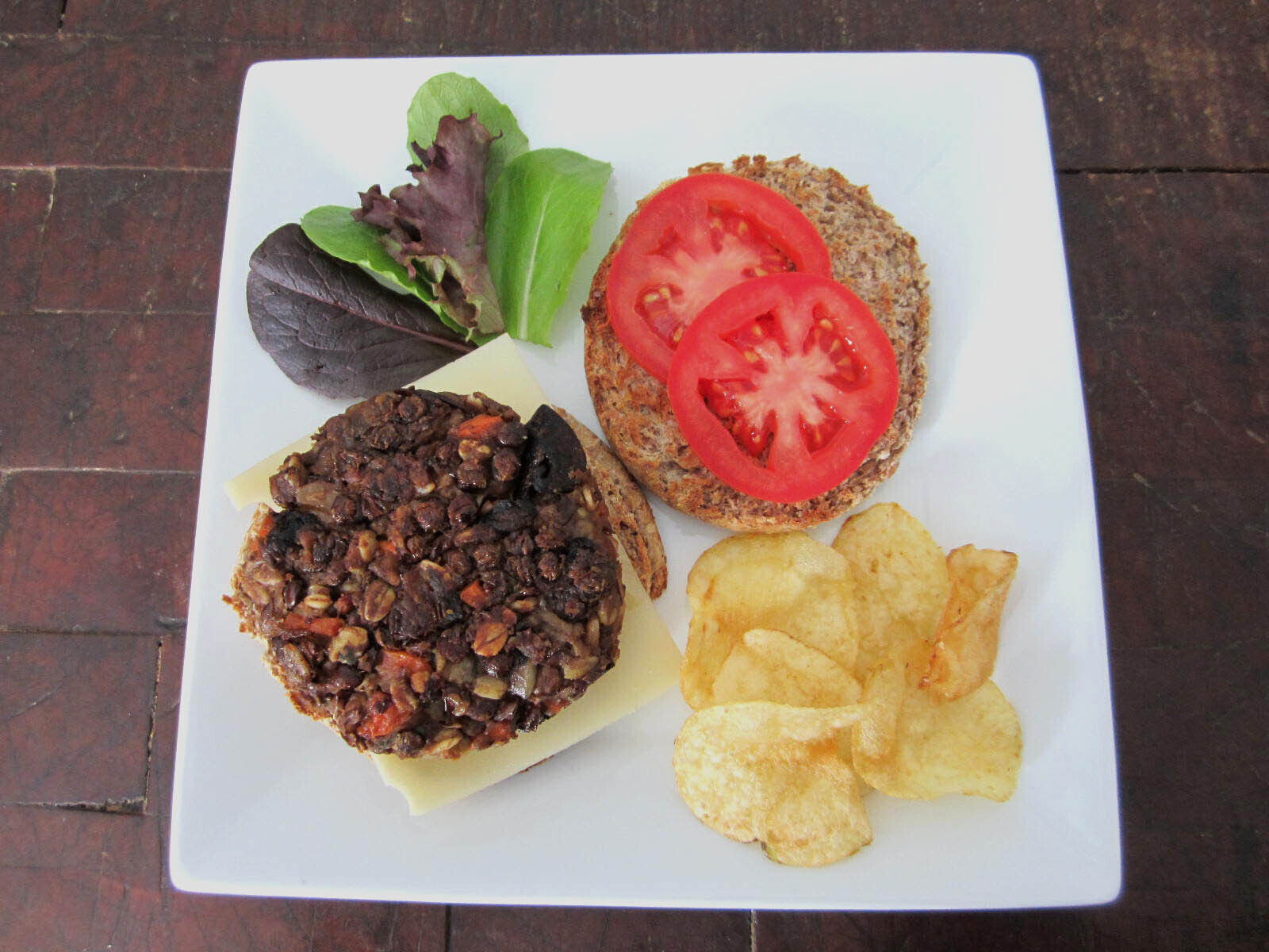 Lentil carrot burgers with cheese, tomatoes, lettuce and chips on the side