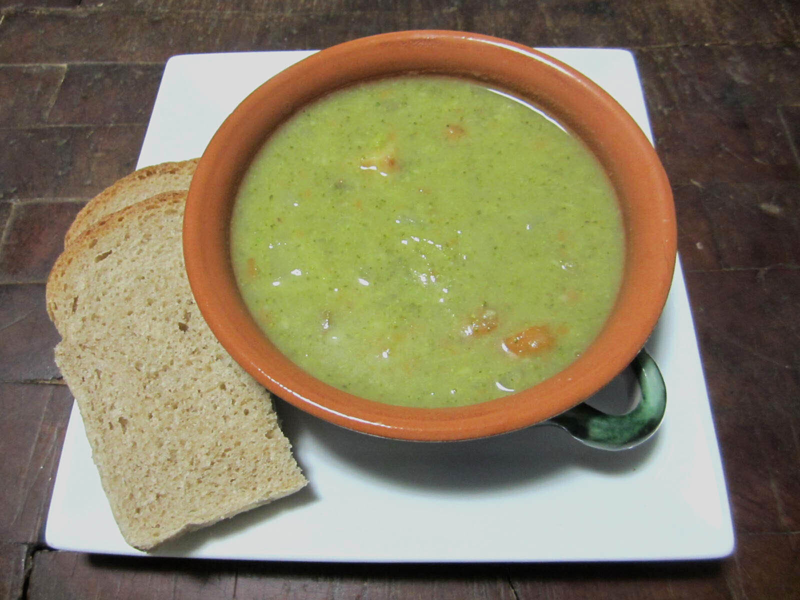 Bowl of broccoli carrot soup with two slices of bread on the side