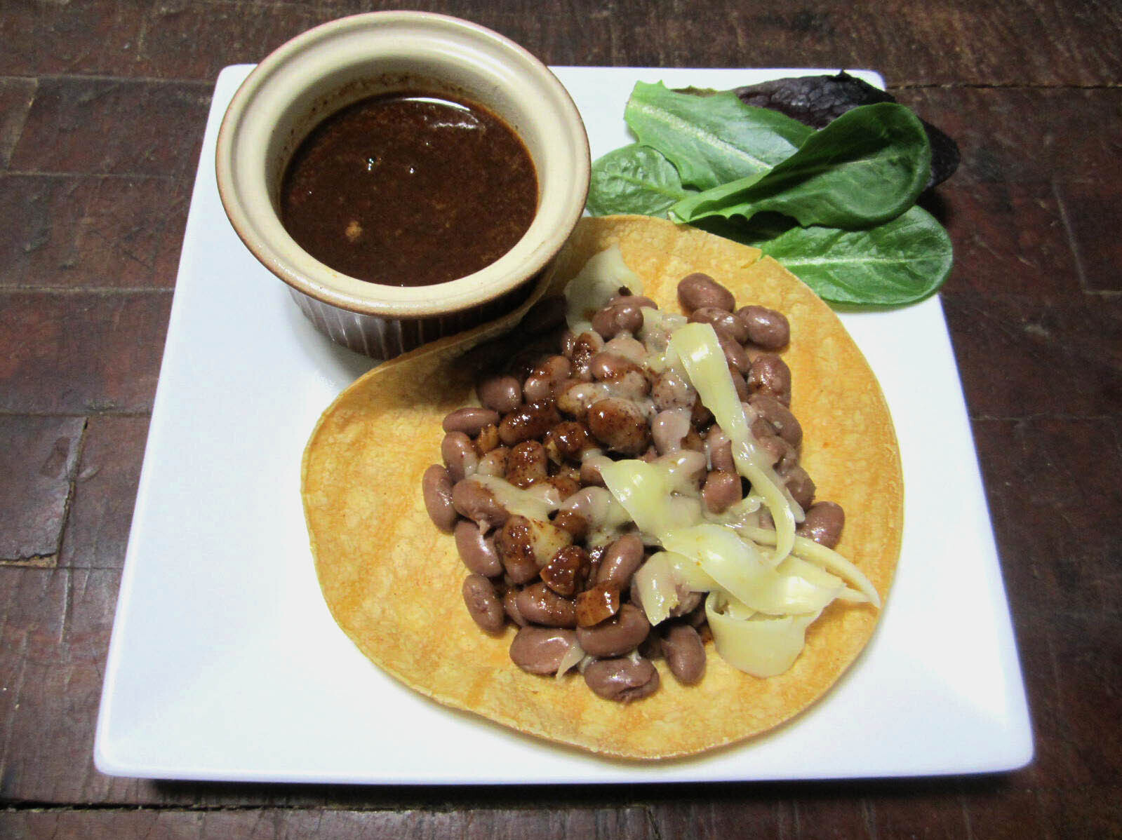 Tortilla served with beans, cheese, lettuce, and sauce