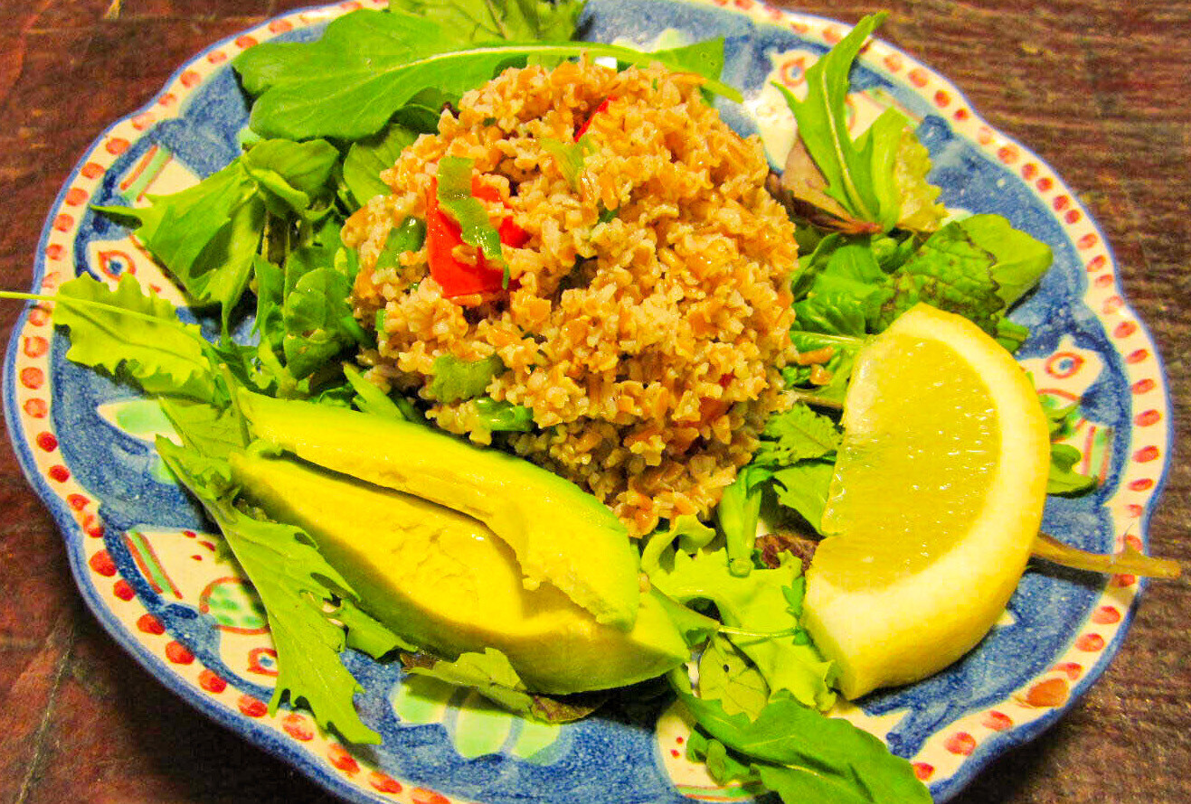 Tabouli salad With Tomato And Avocado on a bed of lettuce with a slice of lemon