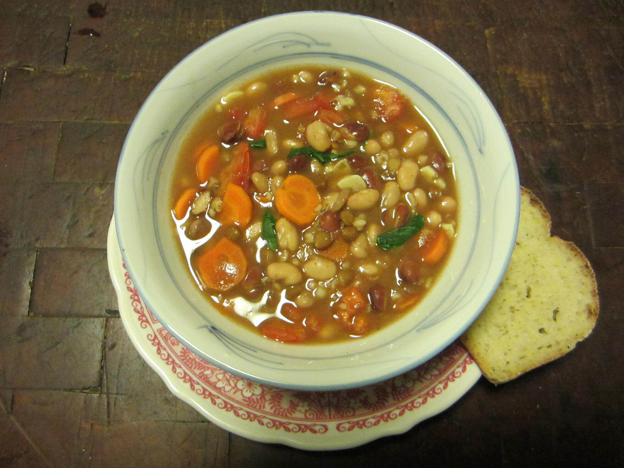 Bowl of vegetable bean soup with a slice of bread on the side