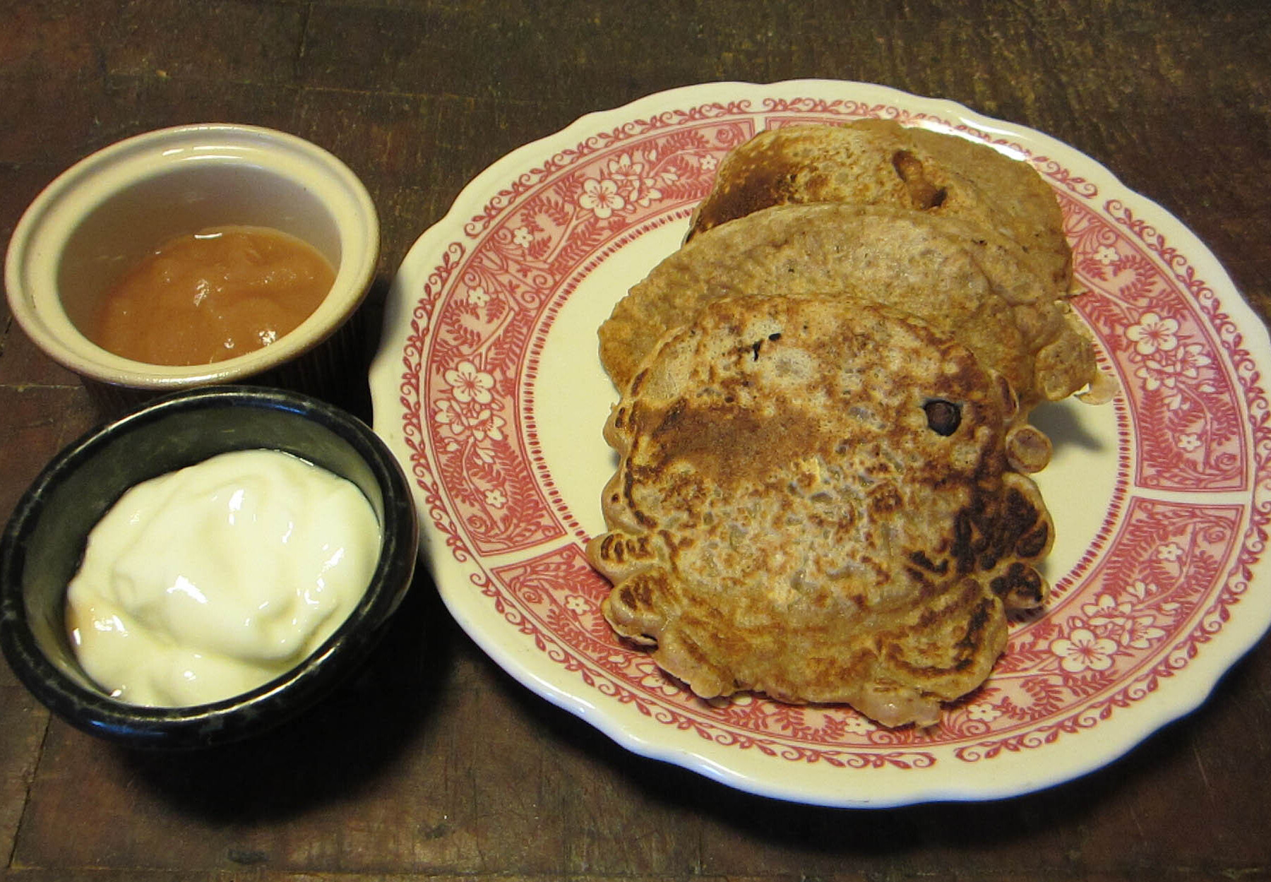 Three wholewheat pancakes served with yogurt and applesauce on the side